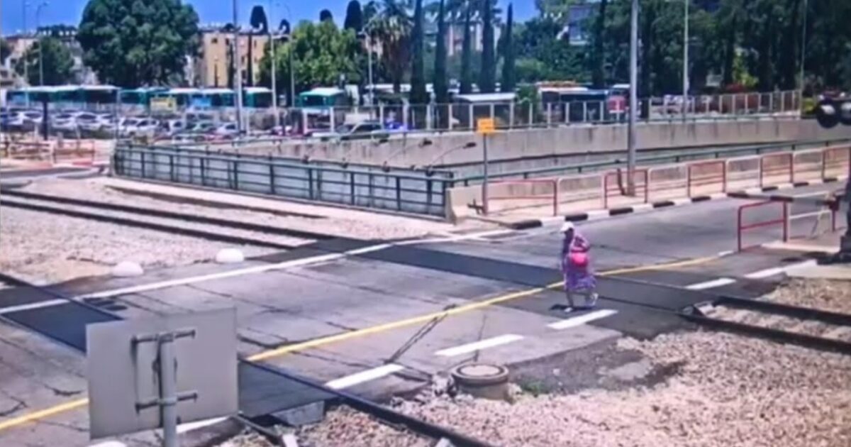 אישה חוצה את מסילת רכבת חיפה כדי לעושת קיצור וגרמה לעצירת הרכבות. צילום: דוברות רכבת ישראל