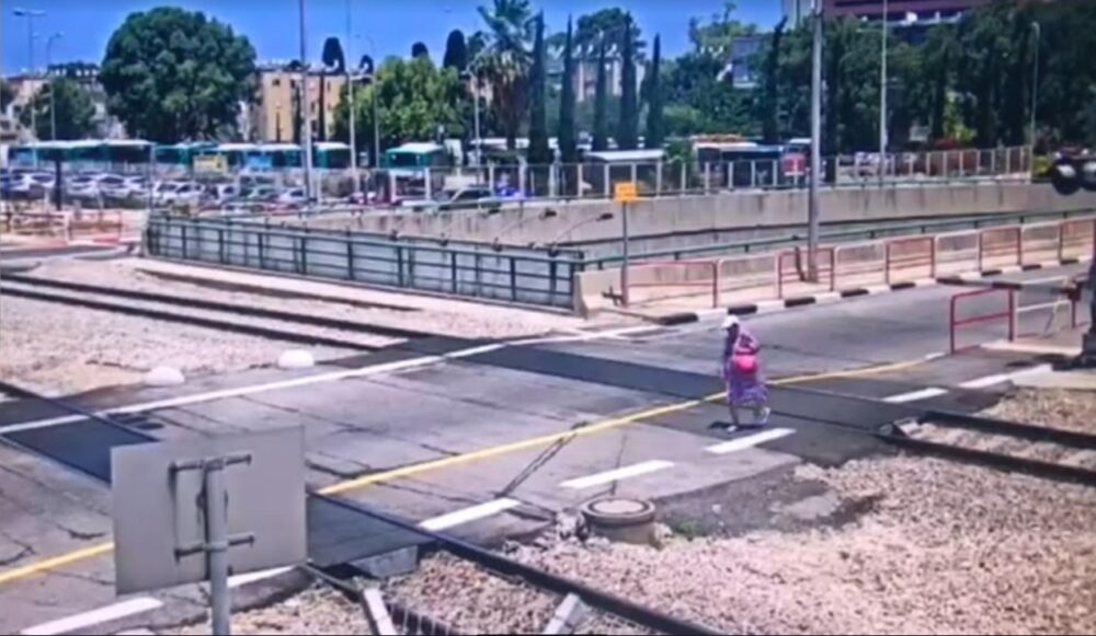 אישה חוצה את מסילת רכבת חיפה כדי לעושת קיצור וגרמה לעצירת הרכבות. צילום: דוברות רכבת ישראל